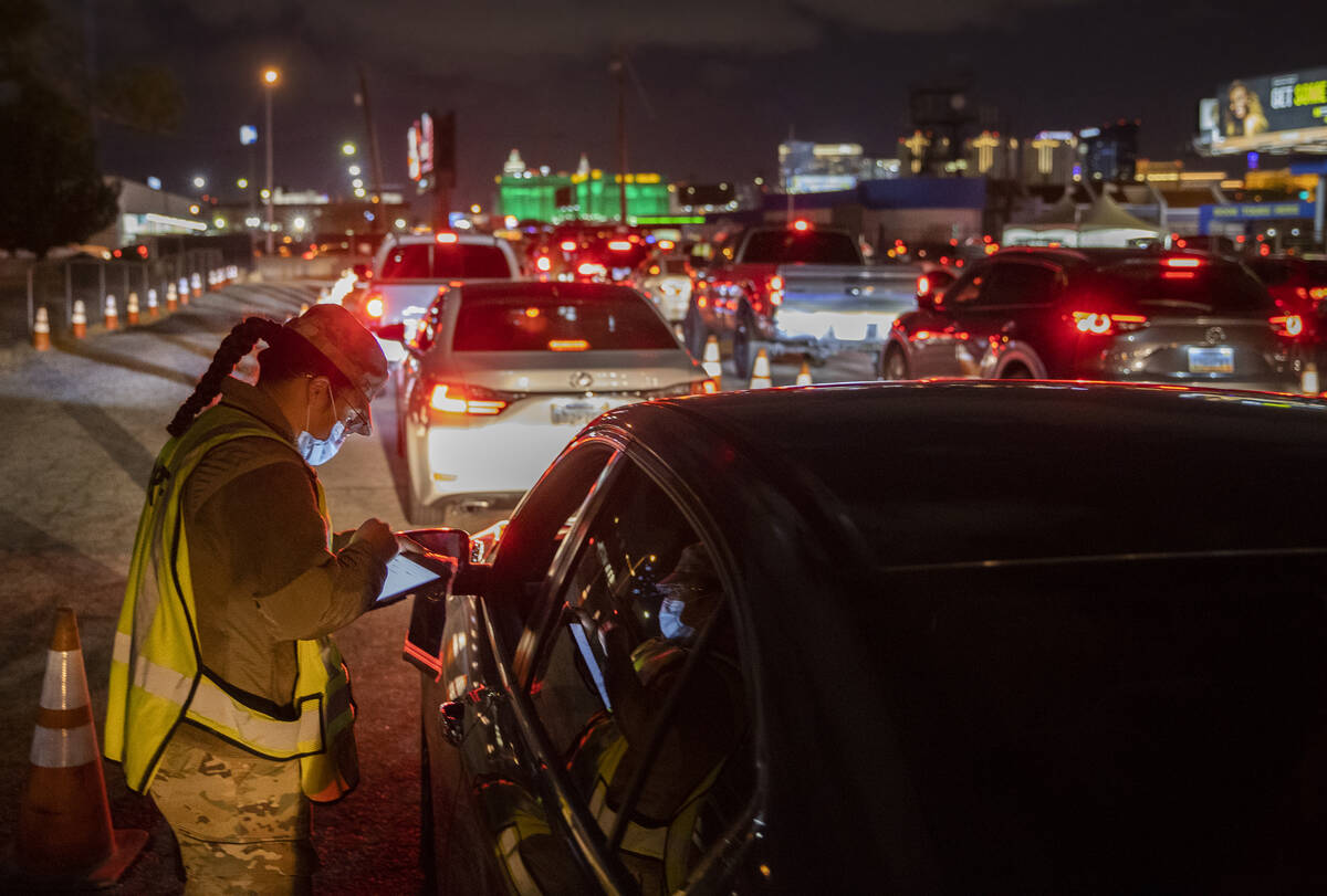 National Guard and emergency medical personnel direct traffic at a drive-thru and walk-up COVID ...