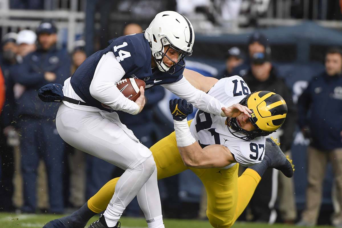 Michigan defensive end Aidan Hutchinson (97) tackles Penn State quarterback Sean Clifford (14) ...