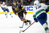 Golden Knights right wing Mark Stone (61) eyes the puck while Canucks defenseman Quinn Hughes ( ...