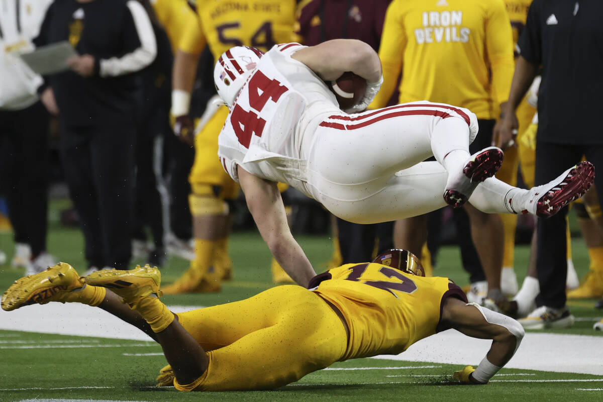 Arizona State defensive back Kejuan Markham (12) tackles Wisconsin fullback John Chenal (44) du ...