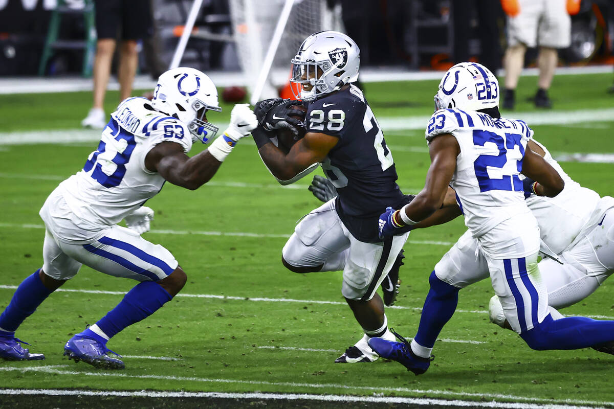 Raiders moving  backmost  Josh Jacobs (28) tries to get   past   Indianapolis Colts defense, including o ...