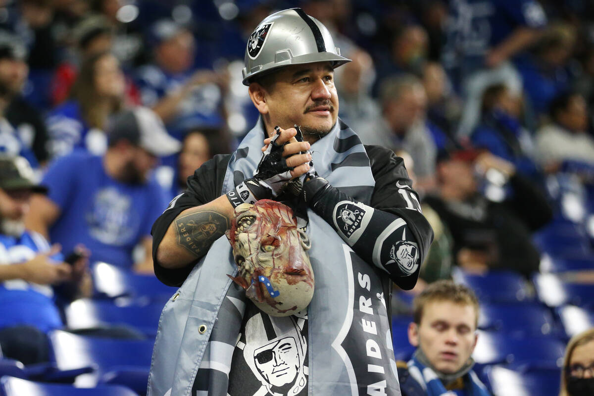 A fan watches player warm up before the start of of an NFL football game between the Raiders an ...