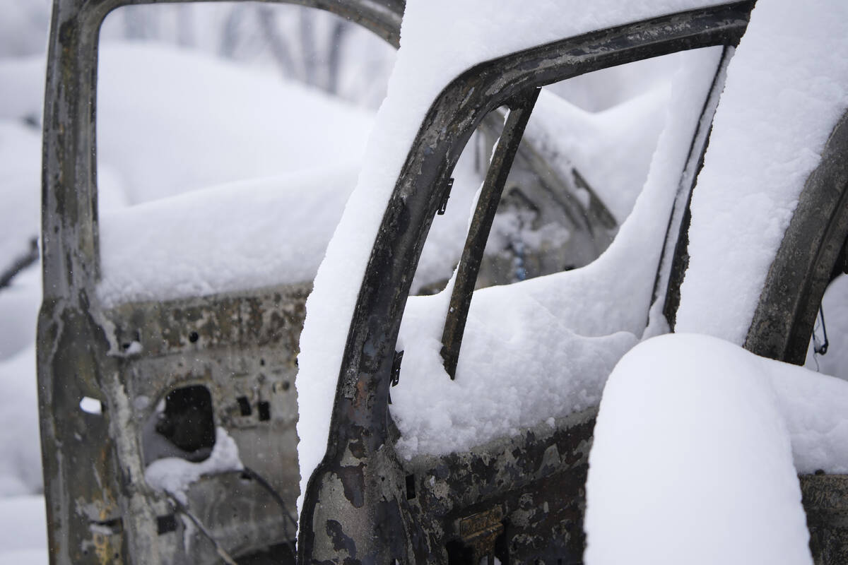 The doors of a chared pickup truck are open near the remains of a home destroyed by a pair of w ...