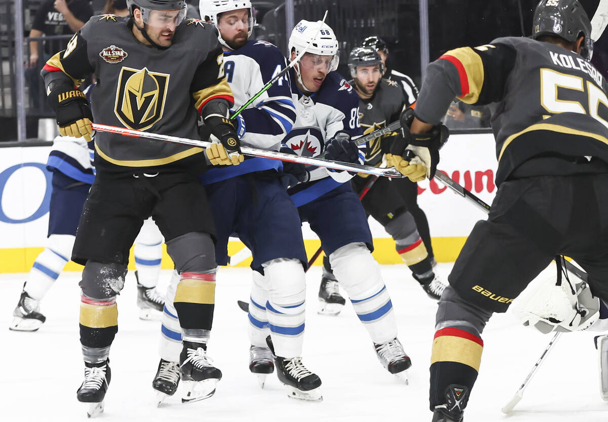 Golden Knights left wing William Carrier, left, battles or position againstWinnipeg Jets defens ...