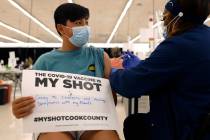 Lucas Kittikamron-Mora, 13, holds a sign in support of COVID-19 vaccinations as he receives his ...
