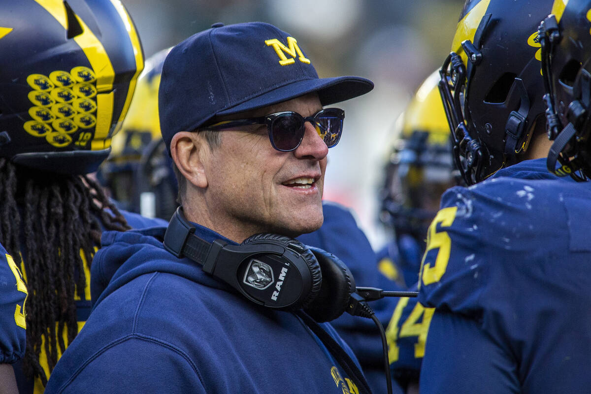 Michigan head coach Jim Harbaugh huddles with his players on the field during a time out in the ...