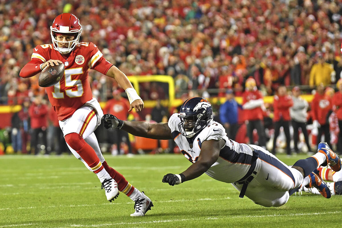 Kansas City Chiefs quarterback Patrick Mahomes (15) scrambles away from Denver Broncos defensiv ...