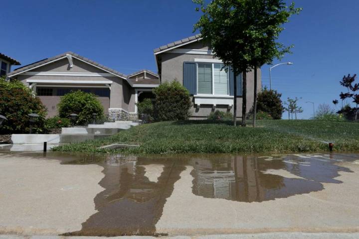 Water flows down a sidewalk from water sprinklers running at a home Thursday, April 2, 2015, in ...