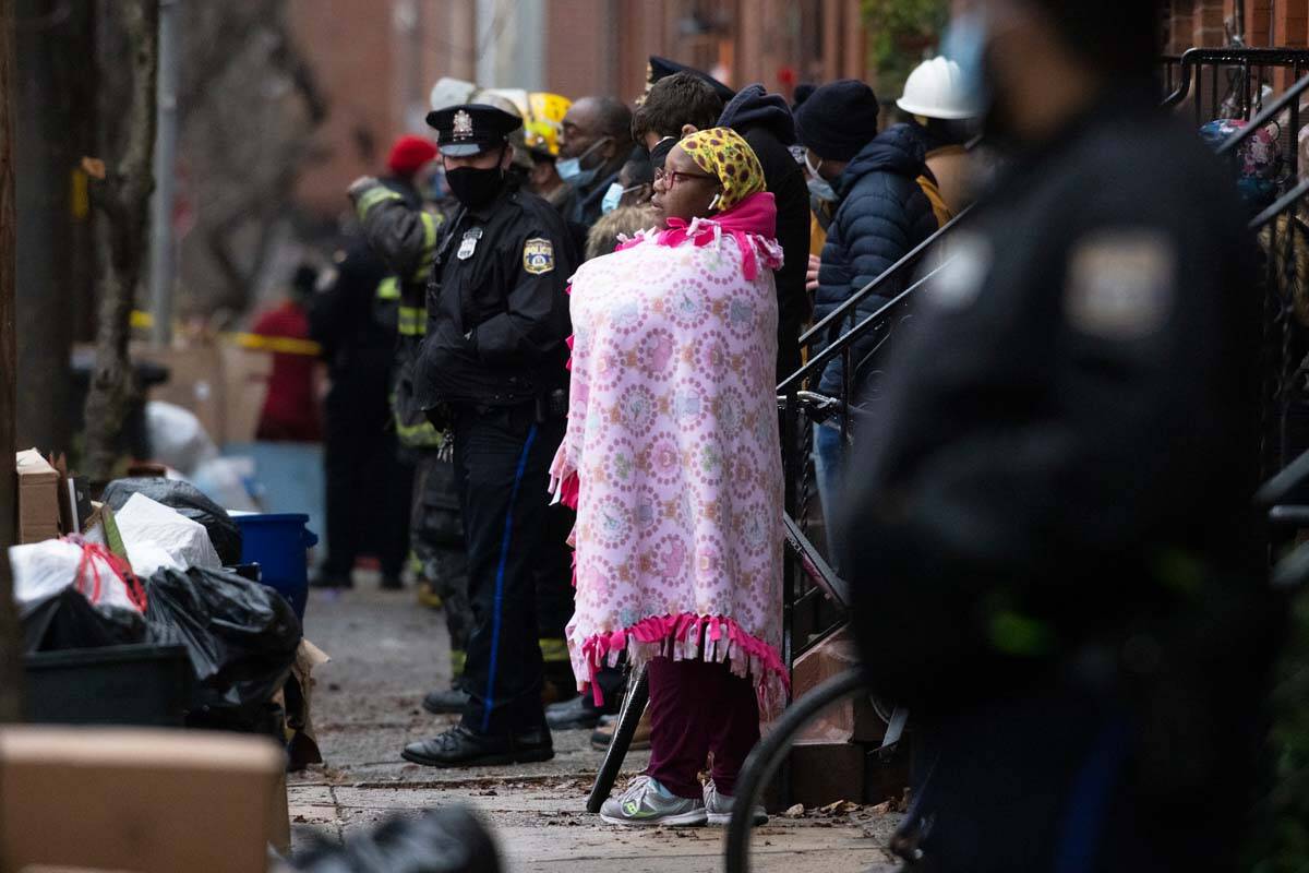 Bystanders watch as the Philadelphia fire department works at the scene of a deadly row house f ...