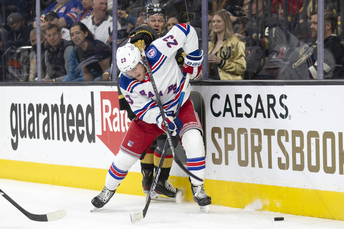 Rangers defenseman Adam Fox (23) slams Golden Knights right wing Evgenii Dadonov (63) into the ...