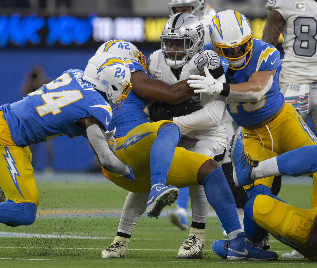 Raiders running back Josh Jacobs (28) is stopped by Los Angeles Chargers linebacker Drue Tranqu ...