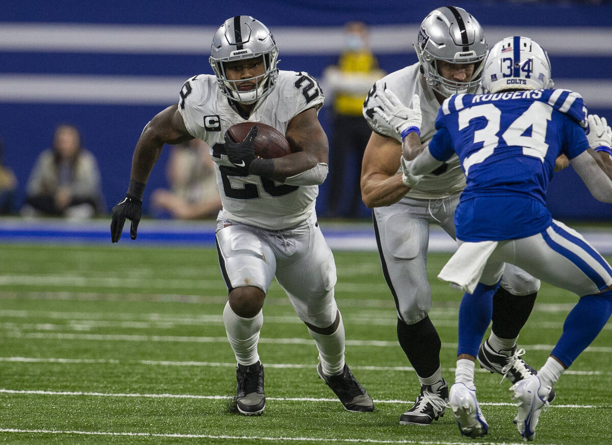 Raiders running back Josh Jacobs (28) runs with the football as Raiders tight end Foster Moreau ...