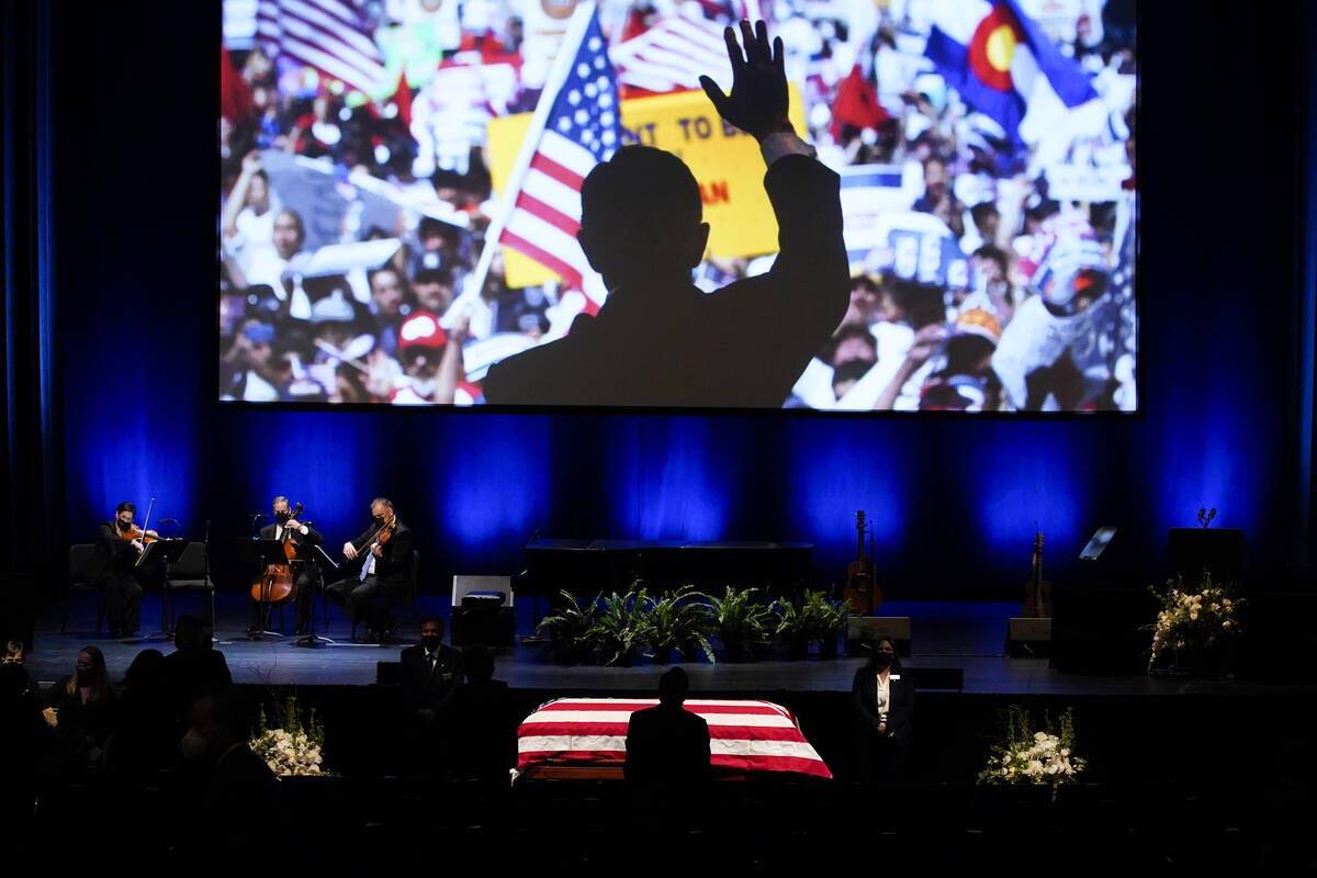 An image of former Senate Majority Leader Harry Reid campaigning is displayed above his flag-draped casked after a memorial service for Reid at the Smith Center in Las Vegas, Saturday, Jan. 8, 2022. (AP Photo/John Locher)
