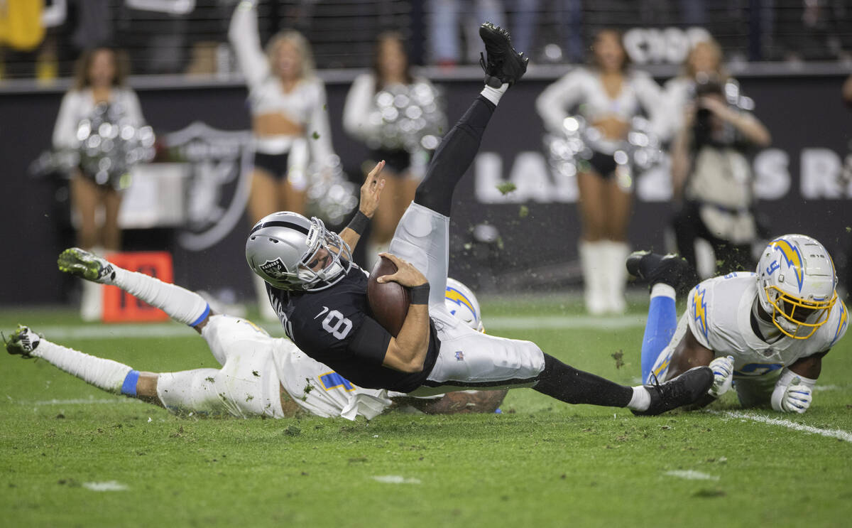 Raiders quarterback Marcus Mariota (8) is tripped up by Los Angeles Chargers middle linebacker ...