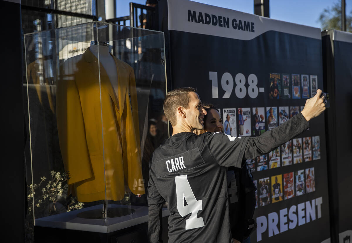 Raiders fans take photos in front of the John Madden memorial exhibit before the start of an NF ...