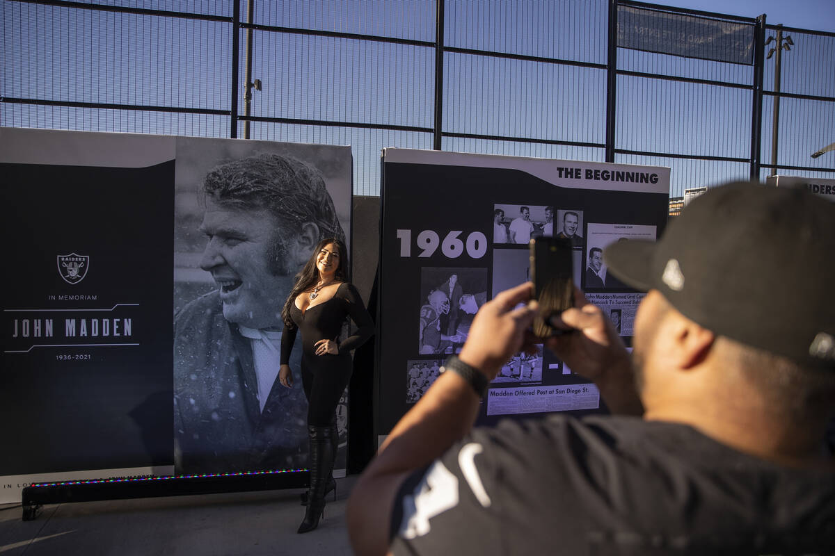 Raiders fans take photos in front of the John Madden memorial exhibit before the start of an NF ...