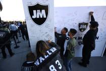 Fans sign a John Madden tribute wall before the start of an NFL football game between the Raide ...