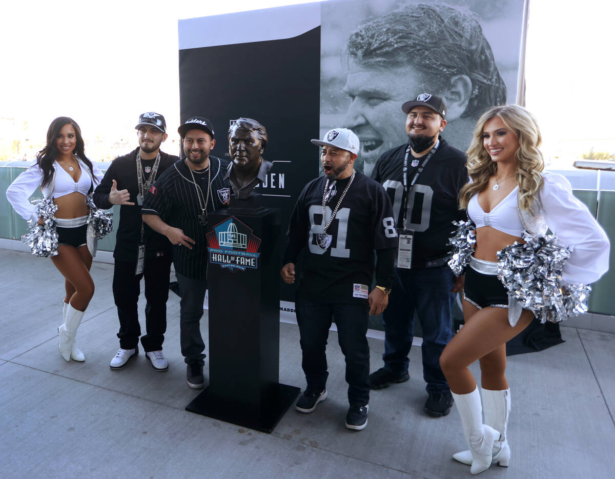 Fans take a photo with a John Madden statue before the start of an NFL football game at Allegia ...