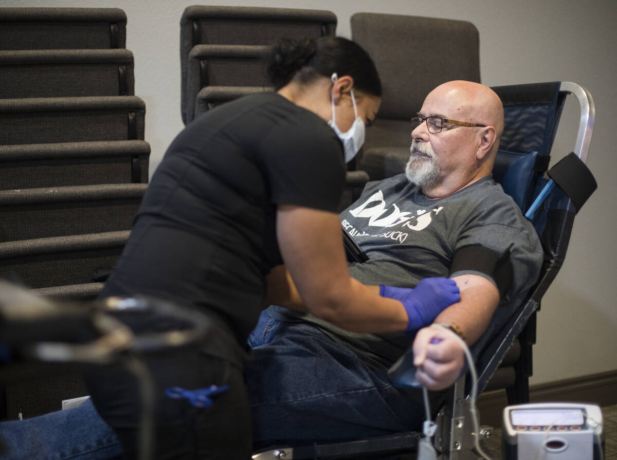 Shae Stanley, a phlebotomist tech, helps Scott Shaw prepare to give blood at a blood drive host ...