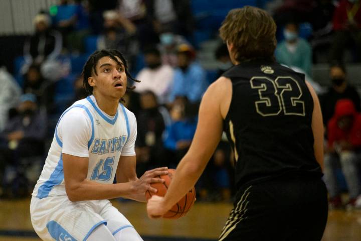 Canyon Springs forward Jalen Foy (15) looks to shoot while Spring Valley forward Carson Dooley ...