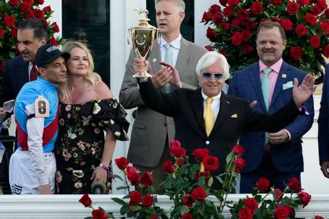 Jockey John Velazquez, left, watches as trainer Bob Baffert holds up the winner's trophy after ...