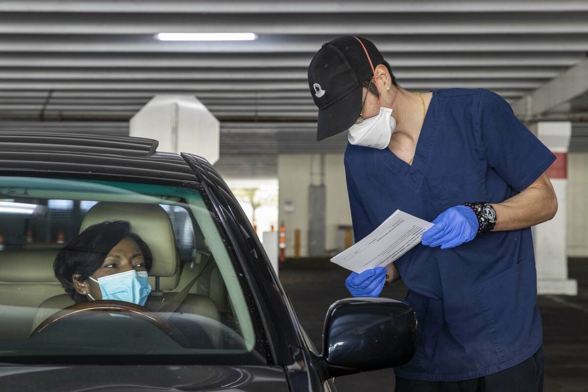 Kenneth Williams, right, verifies the information of Tanya Flanagan before administering a COVI ...