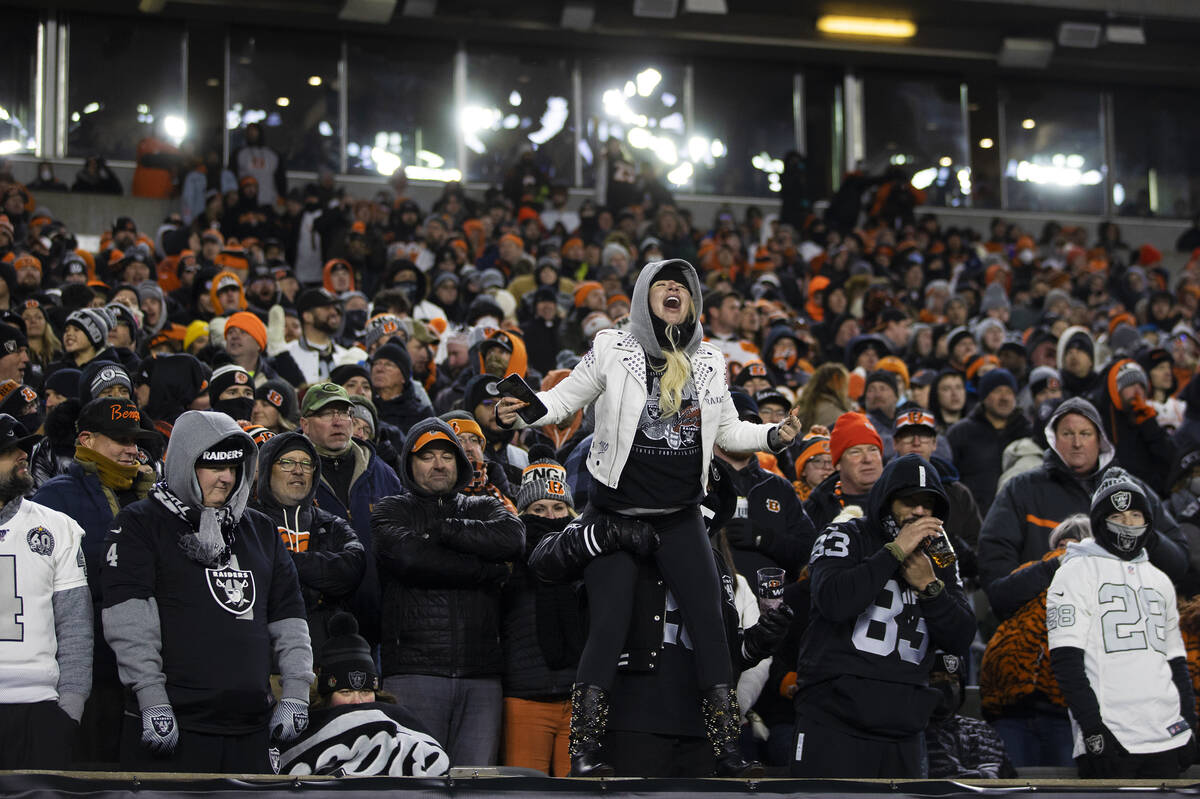 A dejected Raiders fan in a sea of orange leaps on the wall to the field during an NFL playoff ...