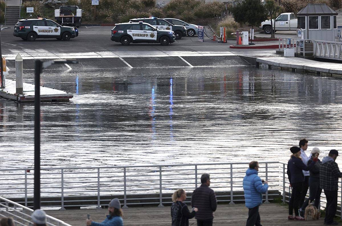 Sheriff's deputies stand by after closing the harbor launch ramp as a tsunami surge flows throu ...