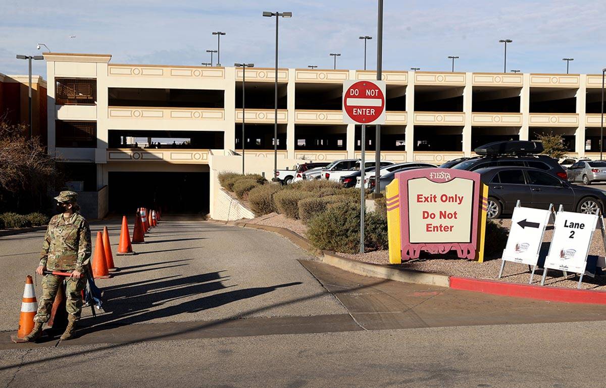 Workers and National Guard members wait for cars at the drive-thru COVID-19 test site at Fiesta ...