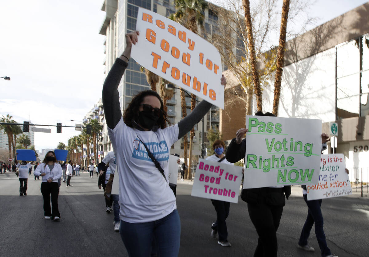 People walk with holding signs about voter rights along Fourth Street during the 40th annual Ma ...