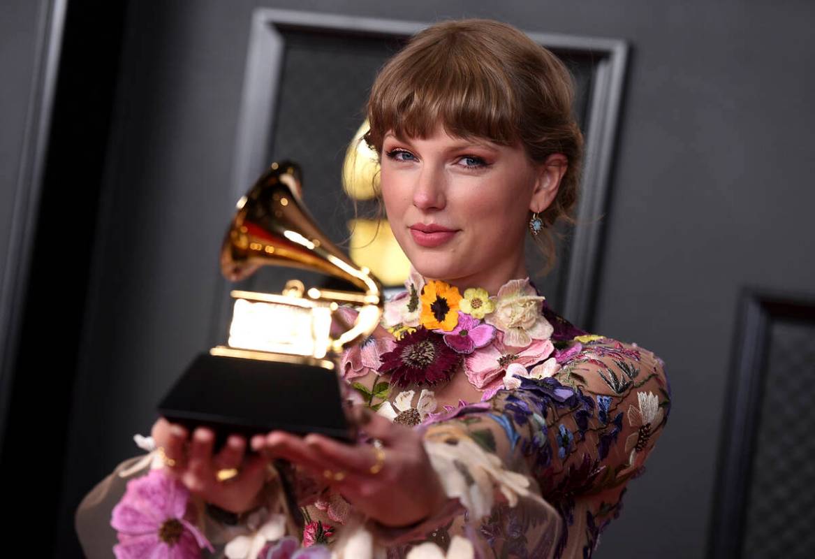 Taylor Swift poses in the press room with the award for album of the year for "Folklore&qu ...