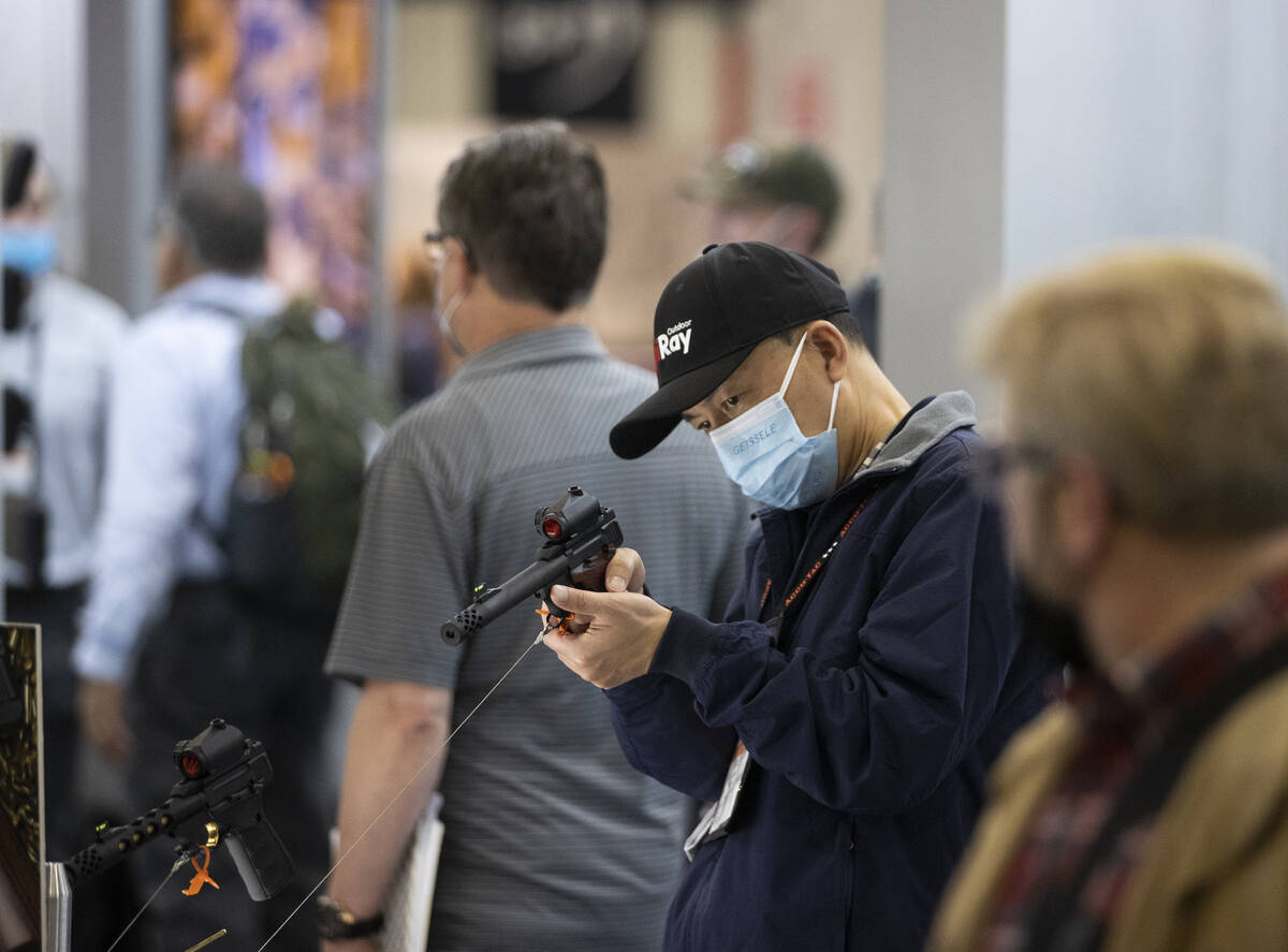 Tao Huang, middle, with iRay Technology, looks at laser scopes during the SHOT Show shooting, h ...