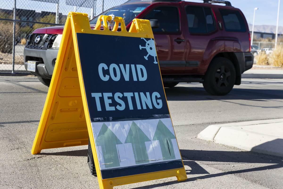 An employee at the Clark County School District drives past a COVID testing sign outside of CCS ...