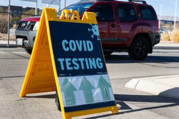 An employee at the Clark County School District drives past a COVID testing sign outside of CCS ...