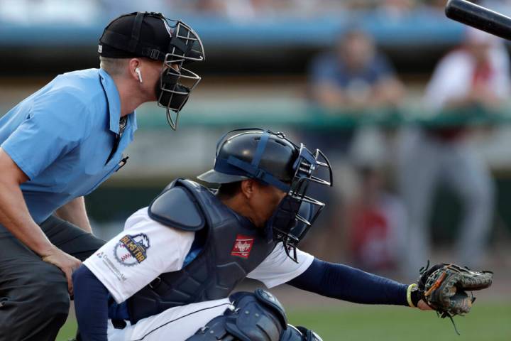 Home plate umpire Brian deBrauwere, left, huddles behind Freedom Division catcher James Skelton ...