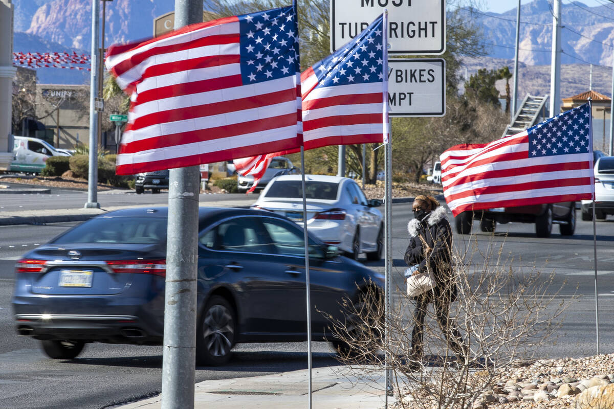 Juanesha Bivens walks along West Sahara Avenue as American flags flutter in the wind on Tuesday ...