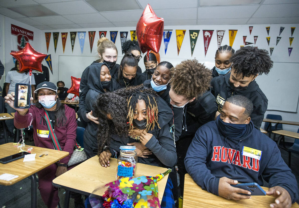 Spring Valley High School basketball guard Aaliyah Gayles, center, is hugged by teammates while ...