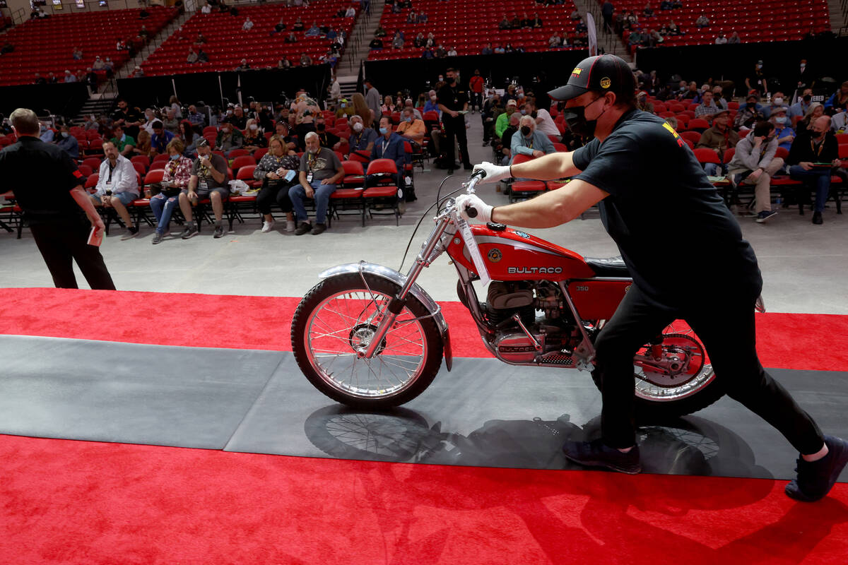 A pusher moves a 1976 Bultaco Sherpa T on the auction block at the Mecum Auctions vintage and a ...