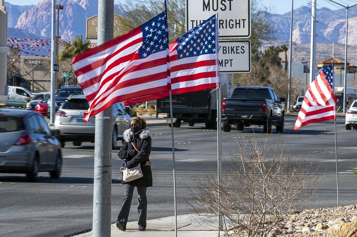 Juanesha Bivens walks along West Sahara Avenue as American flags flutter in the wind on Tuesday ...