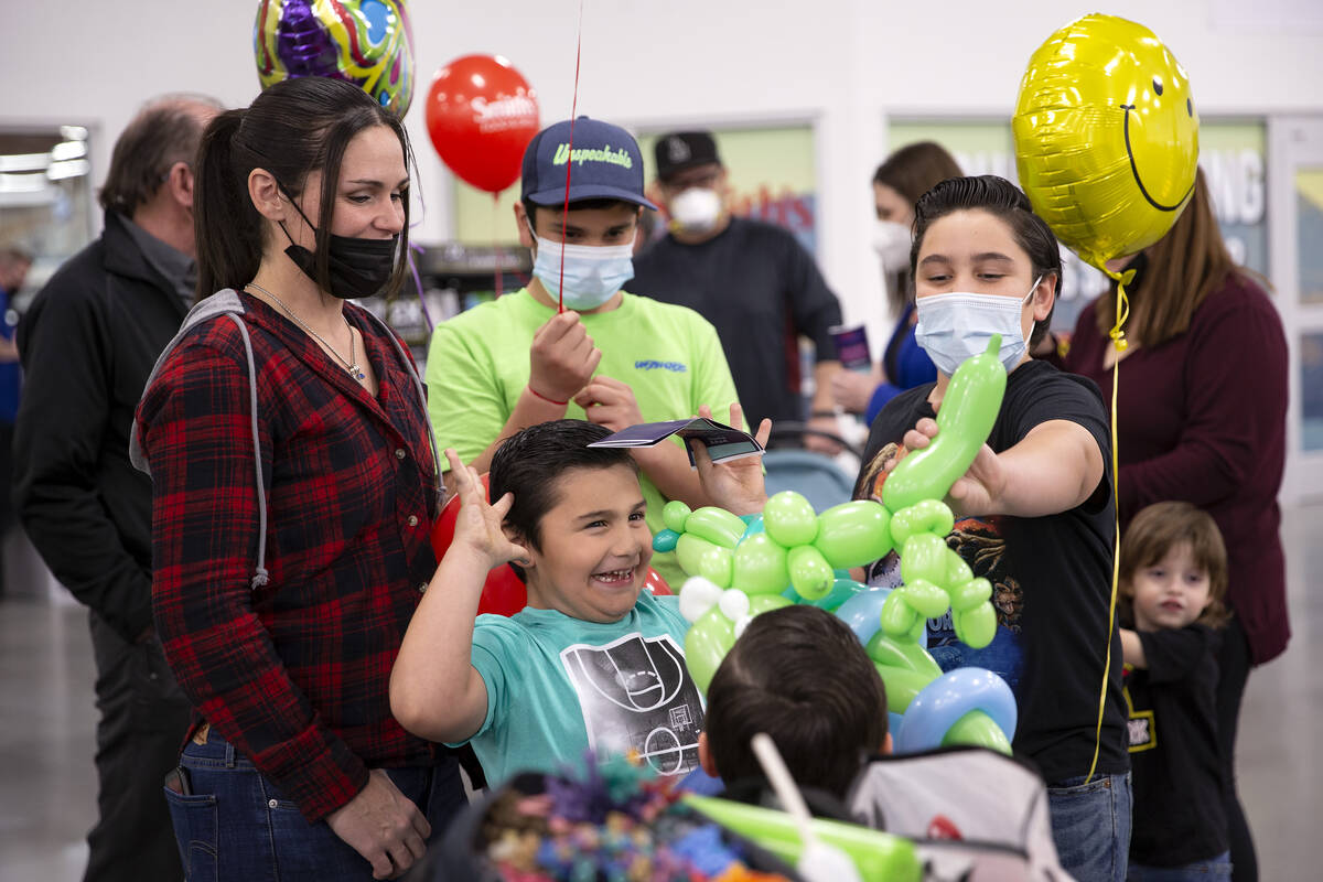 The Cervantes family wait in line for balloon animals during a preview celebration for the new ...