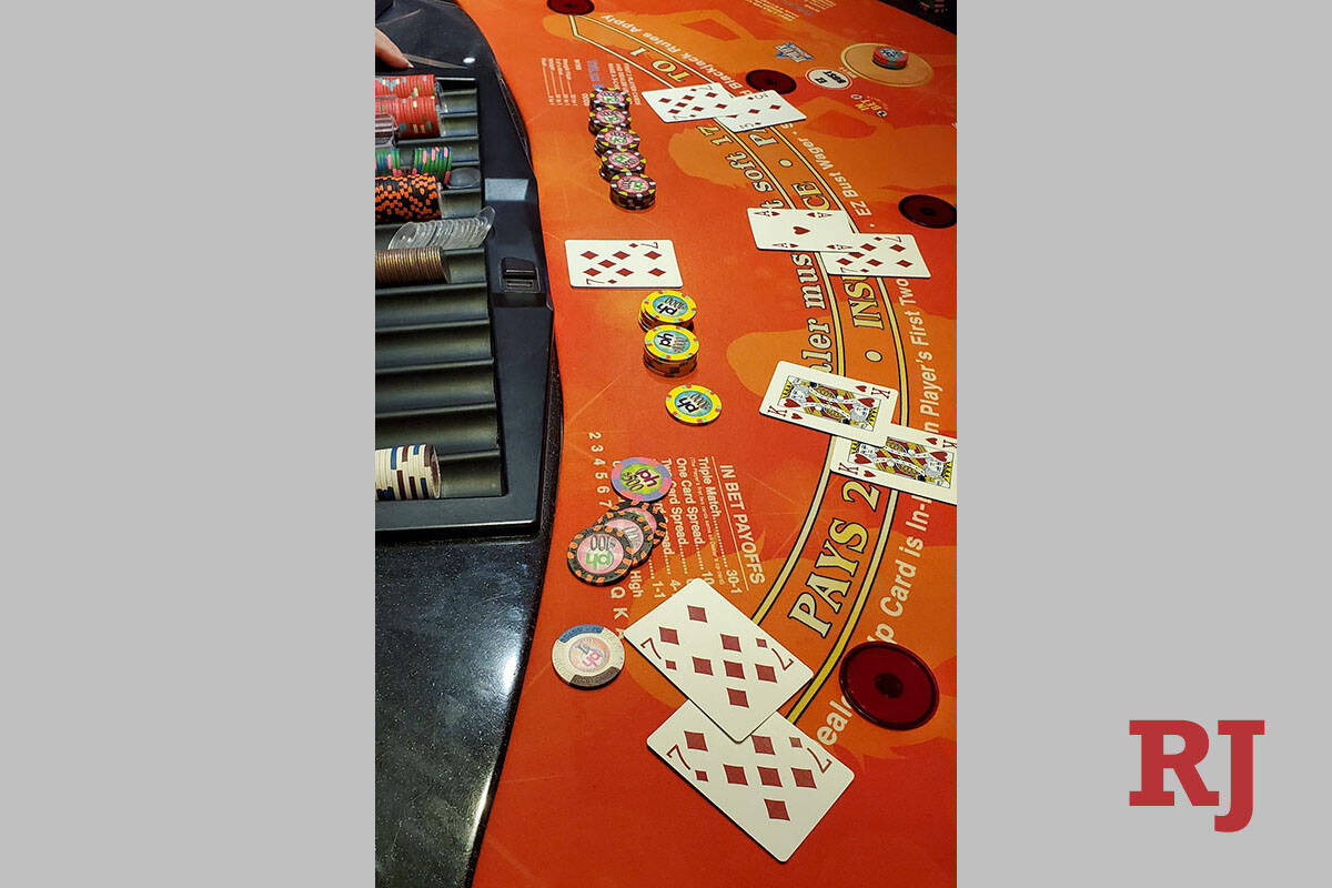 The winning hand (bottom) of two 7 of diamonds with a 7 of diamonds for the blackjack dealer re ...