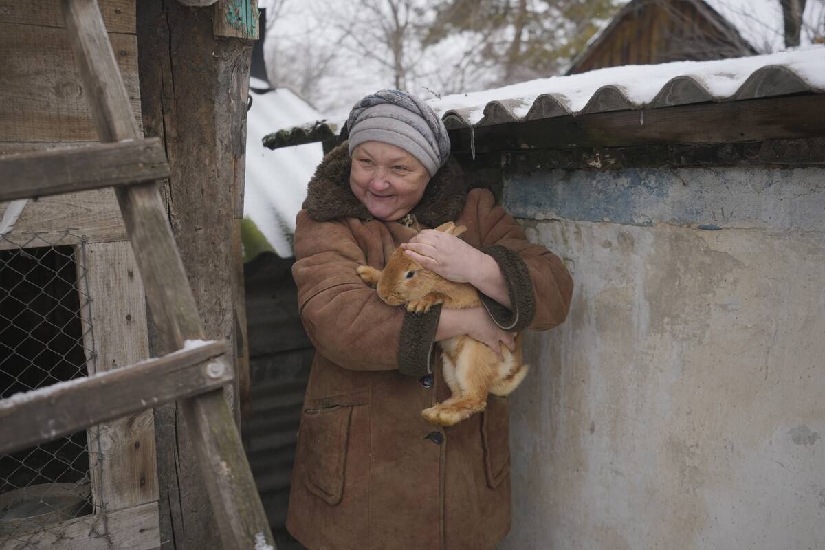 Olga, one of the 16 residents still living in a frontline village, holds a rabbit speaking to j ...