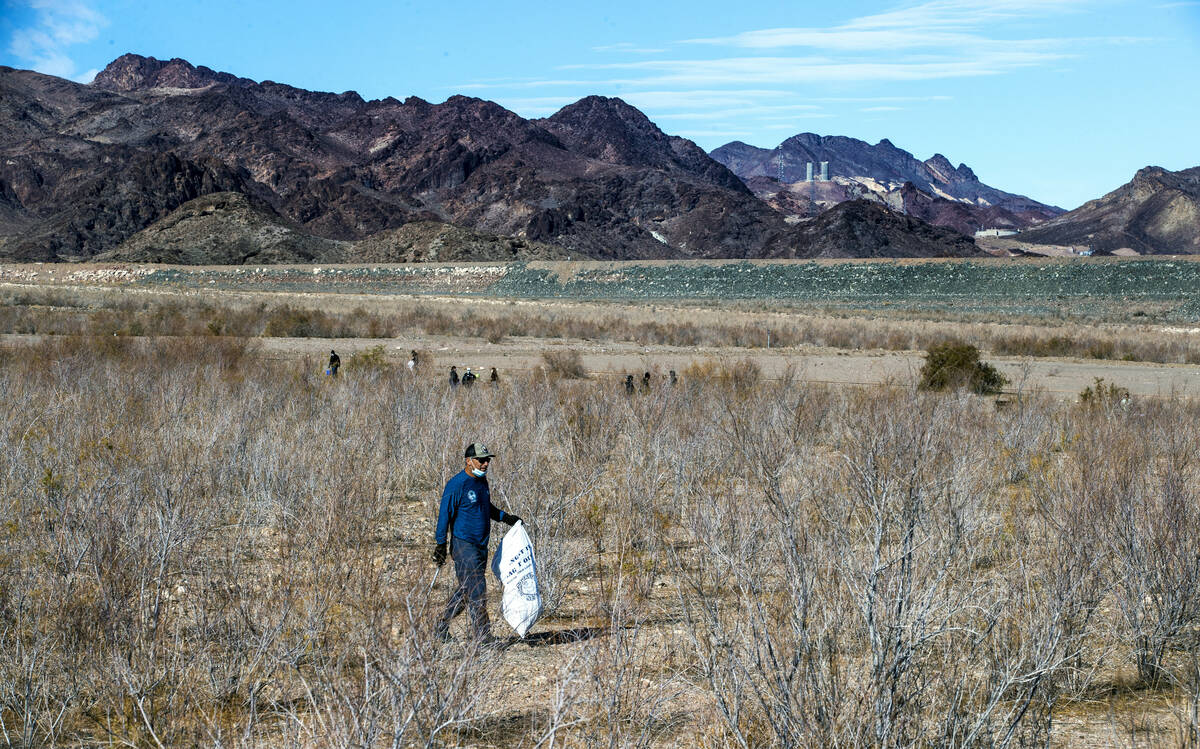 Chris Cheney with Evolution Expeditions picks up trash in brush as his organization and Get Out ...