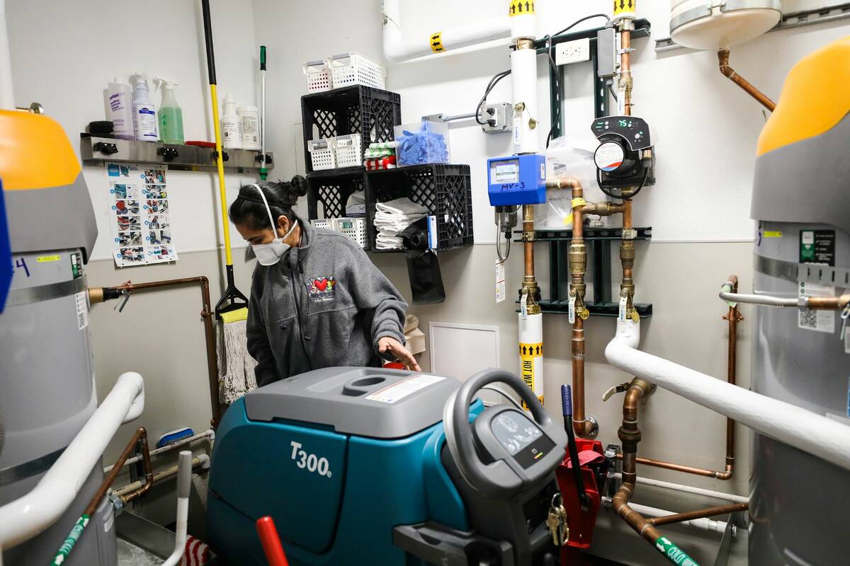 Head custodian Sonia Fernandez fills a Tennant walk-behind floor scrubber at Ferron Elementary ...