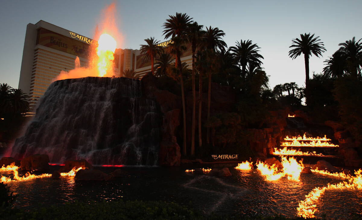 Fire belches from the volcano as fames dance across the surface of the water in front of The Mi ...