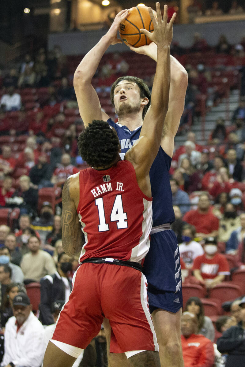 Nevada Wolf Pack center Will Baker (50) shoots against UNLV Rebels forward Royce Hamm Jr. (14) ...