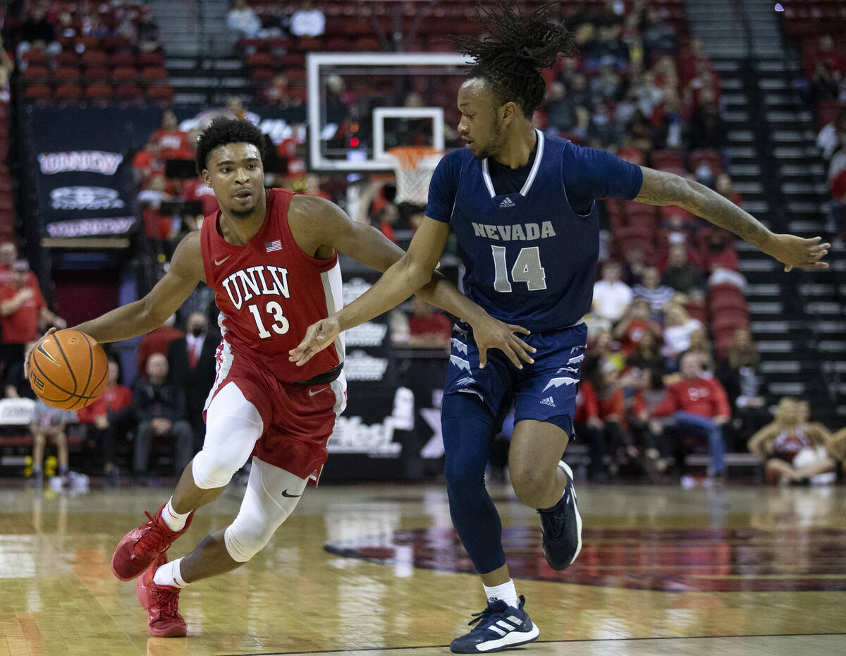 UNLV Rebels guard Bryce Hamilton (13) dribbles up the court while Nevada Wolf Pack forward Tre ...
