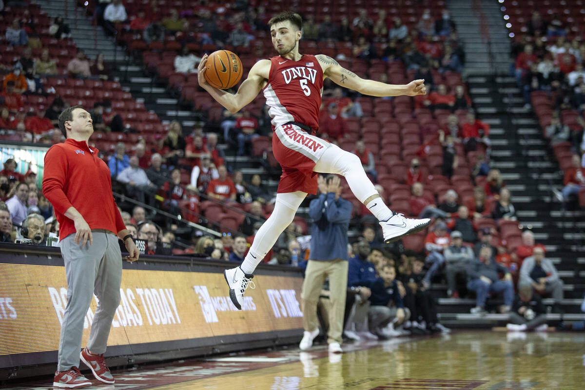 UNLV Rebels guard Jordan McCabe (5) catches a pass while head coach Kevin Kruger ducks away dur ...
