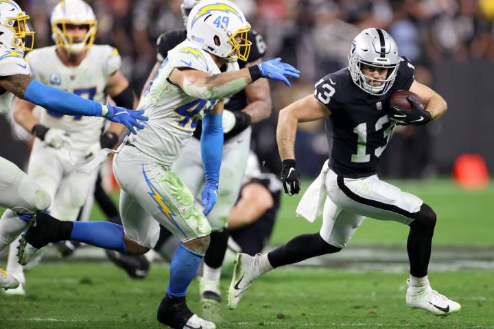 Raiders wide receiver Hunter Renfrow (13) runs the ball under pressure from Los Angeles Charger ...