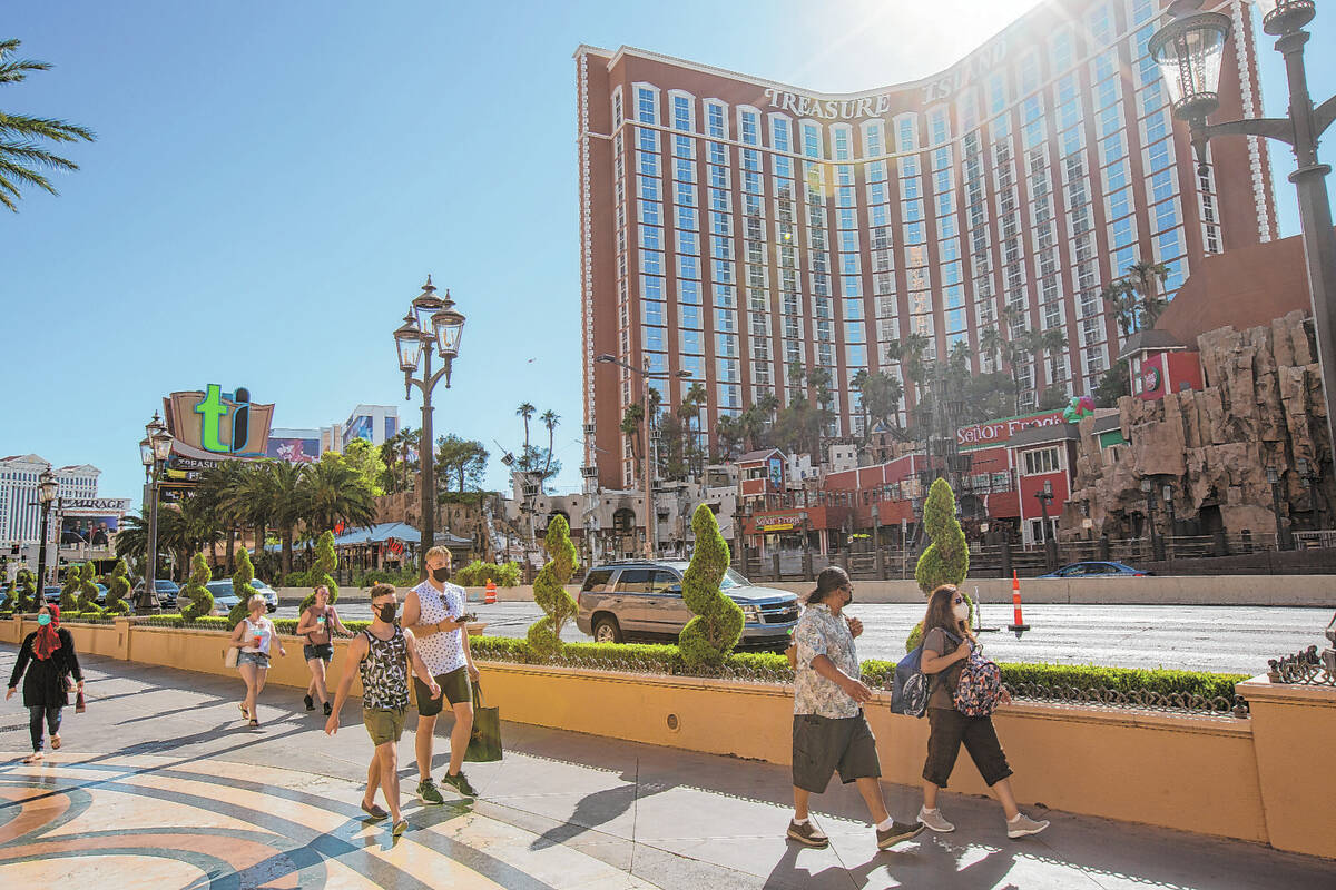 People walk down the Strip in front of Treasure Island in Las Vegas on Friday, July 3, 2020. (L ...
